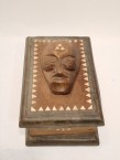 une caisse avec une masque sur le couverture et décoré avec du nacre